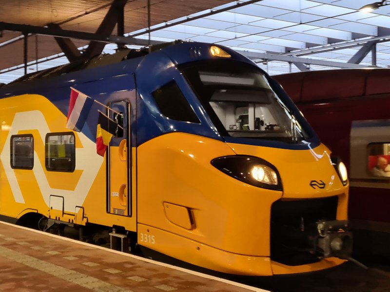 De aankomt van de trein op Rotterdam Centraal waarbij de vlaggen de samenwerking benadrukken. (Foto: Treinenweb.nl)